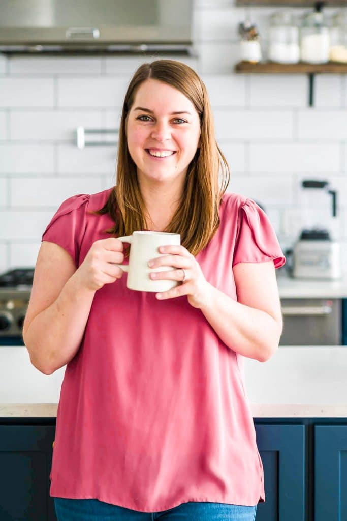 a photo of a woman in a pink shirt holding a mug.