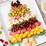 A charcuterie board in the shape of a Christmas tree on a white sheen pan.