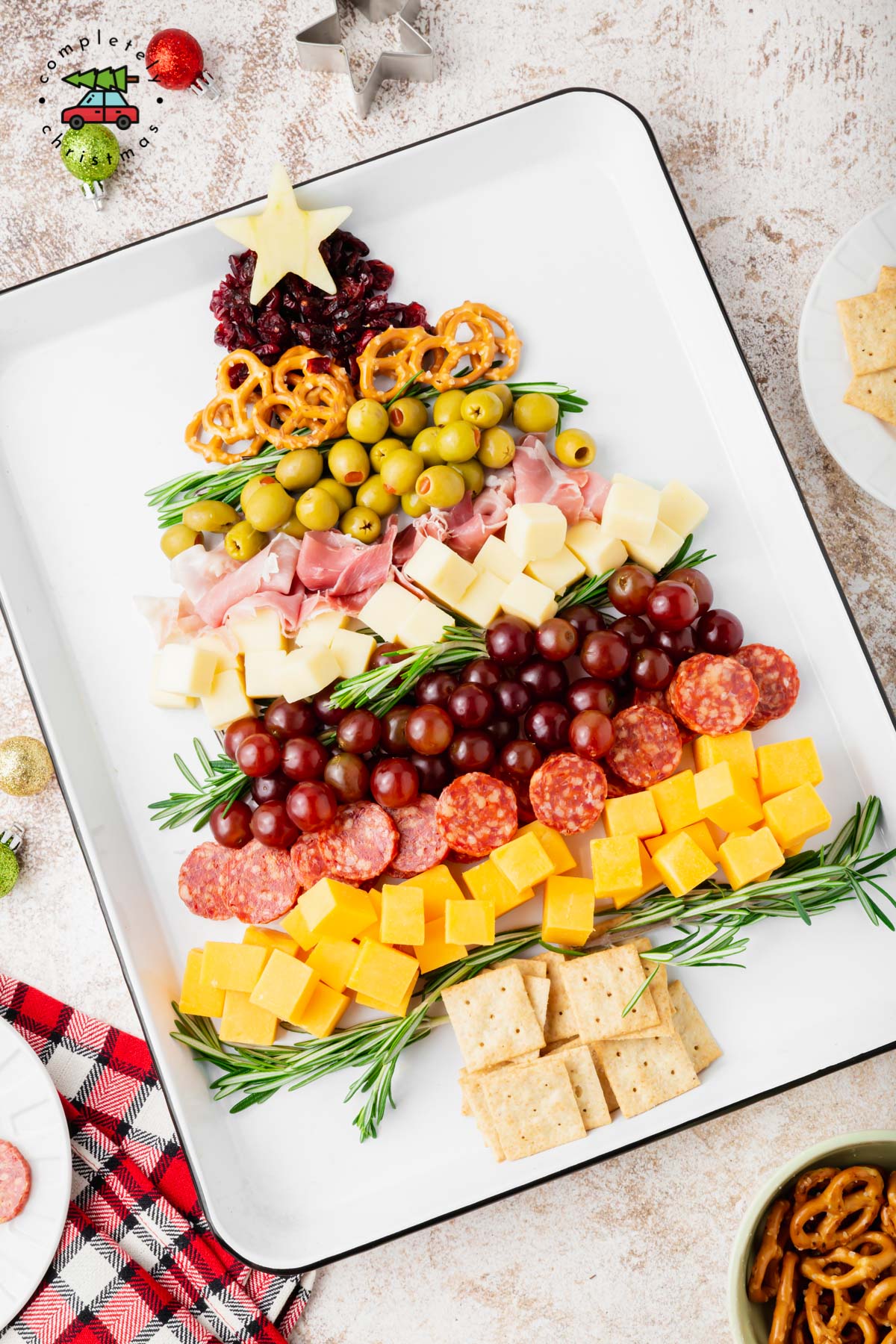 A charcuterie board in the shape of a Christmas tree on a white sheen pan. 