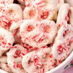 A closeup of white chocolate candy cane covered pretzels in a bowl.