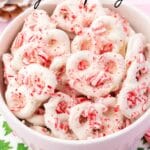 A bowl of white chocolate pretzels with candy canes on top.