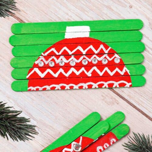 A Christmas popsicle stick puzzle that is decorated with an ornament design and is partially put together.