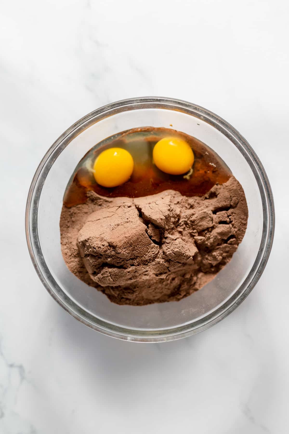 A bowl of brownie mix and 2 eggs before mixing together.