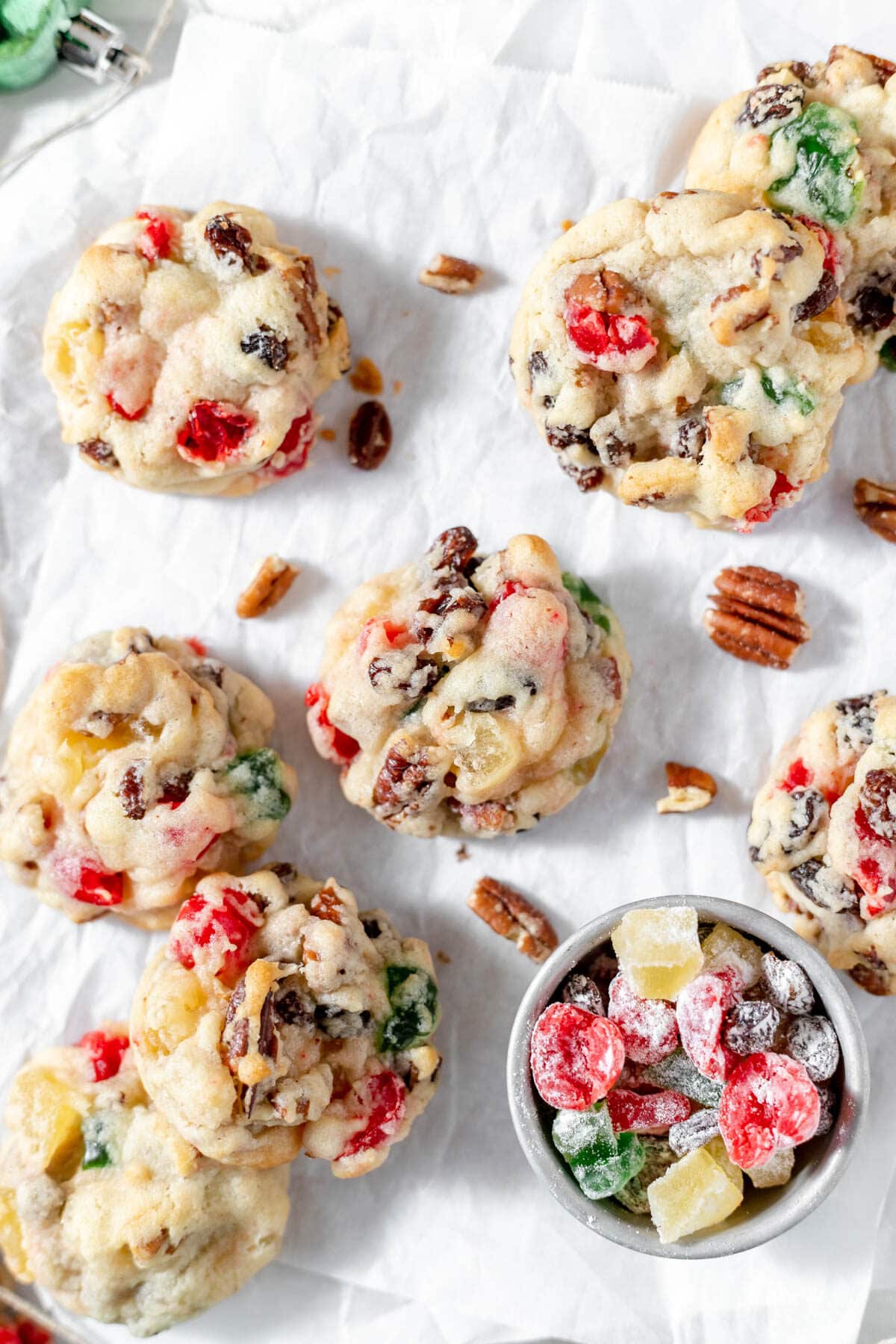 Fruitcake cookies spread out on parchment paper.