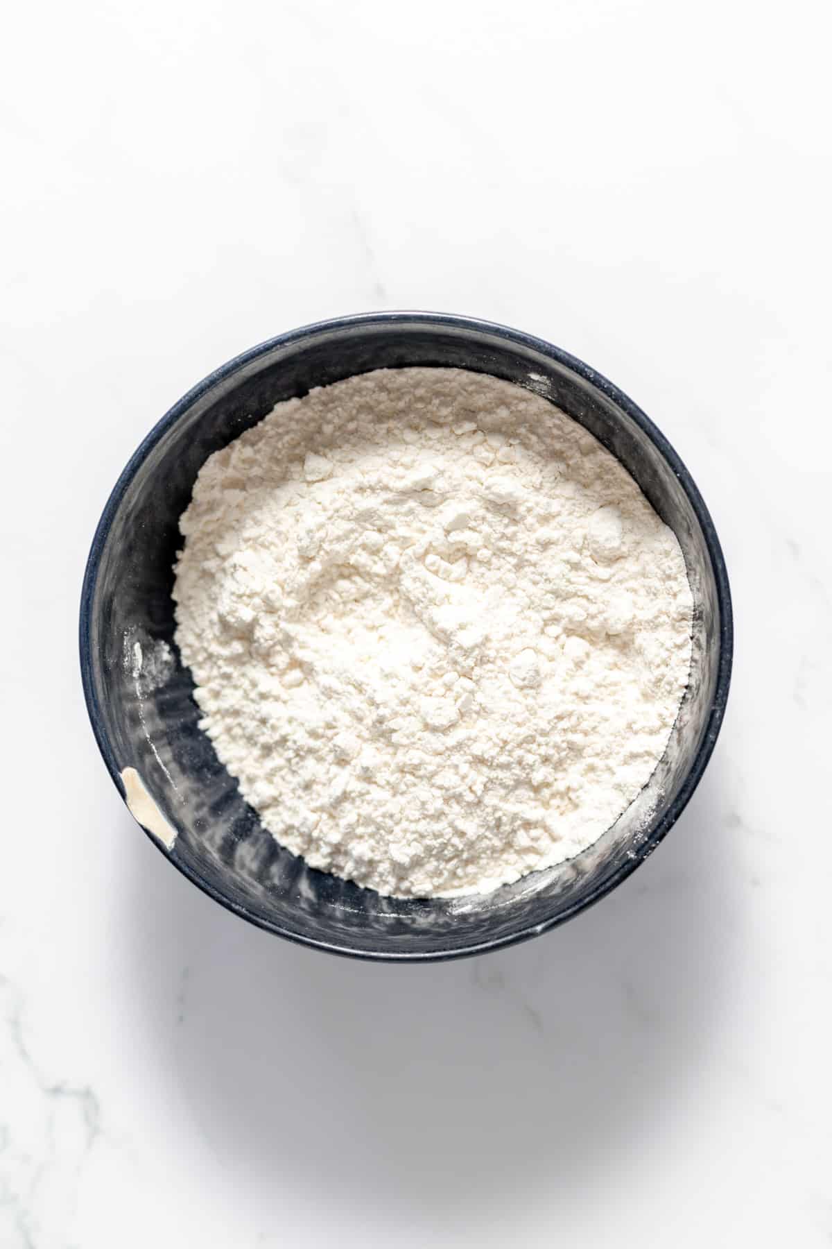 A mixing bowl with all-purpose flour, salt, and baking soda in it.