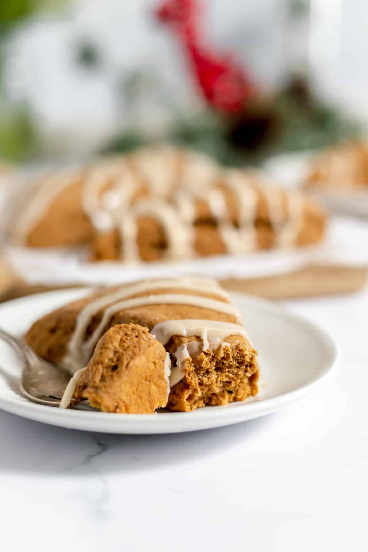 A gingerbread scone on a plate with a bite taken out of it with more gingerbread scones in the background.