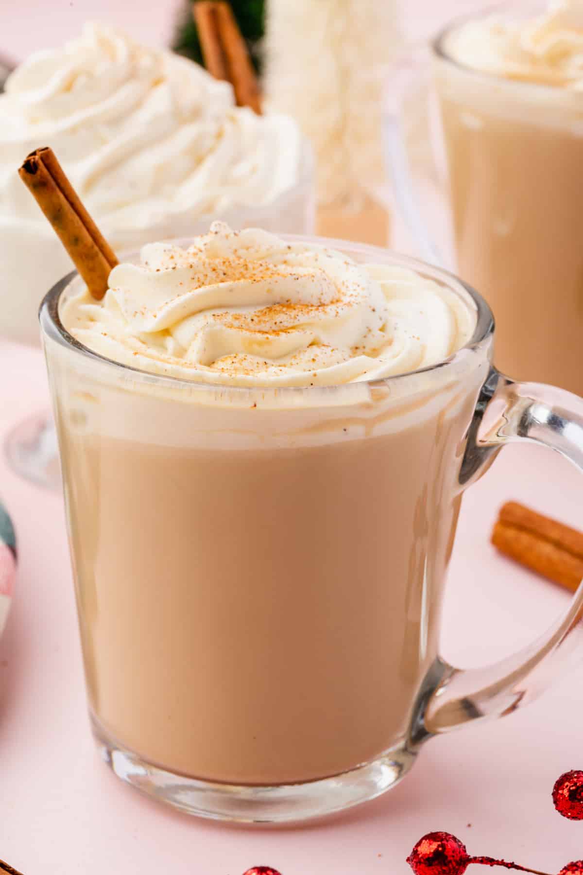 A mug of eggnog coffee topped with whipped cream, a sprinkle of nutmeg and a cinnamon stick.