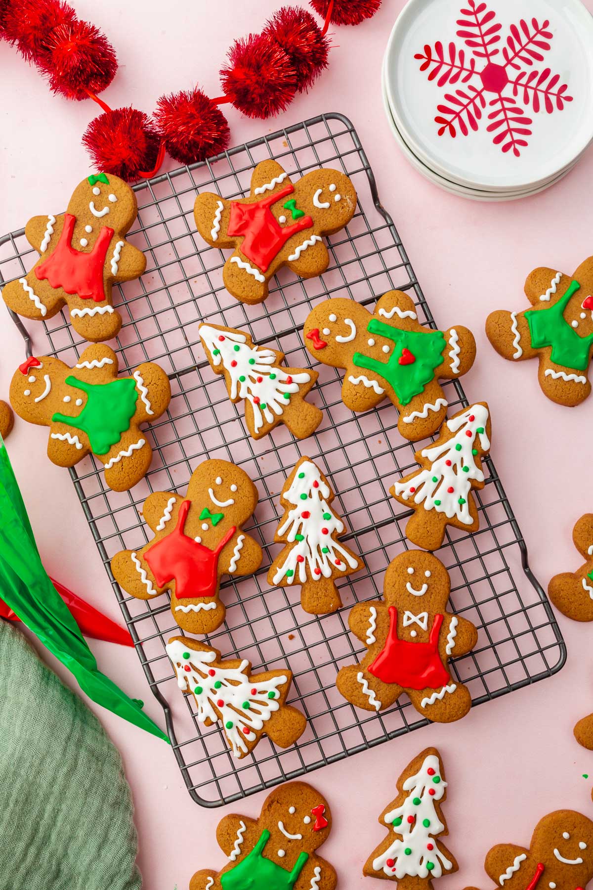 A wire cooling rack with decorated gingerbread cookies that look like Christmas trees and gingerbread men with red, white and green royal icing.