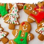 A close up of gingerbread cookies decorated with royal icing in red, green and white to look like Christmas trees and gingerbread men.