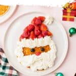 A large pancake decorated with strawberries, raspberries, and whipped cream to look like Santa Claus.
