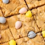A closeup of Easter blondies cut into squares and topped with mini Cadbury chocolate eggs.