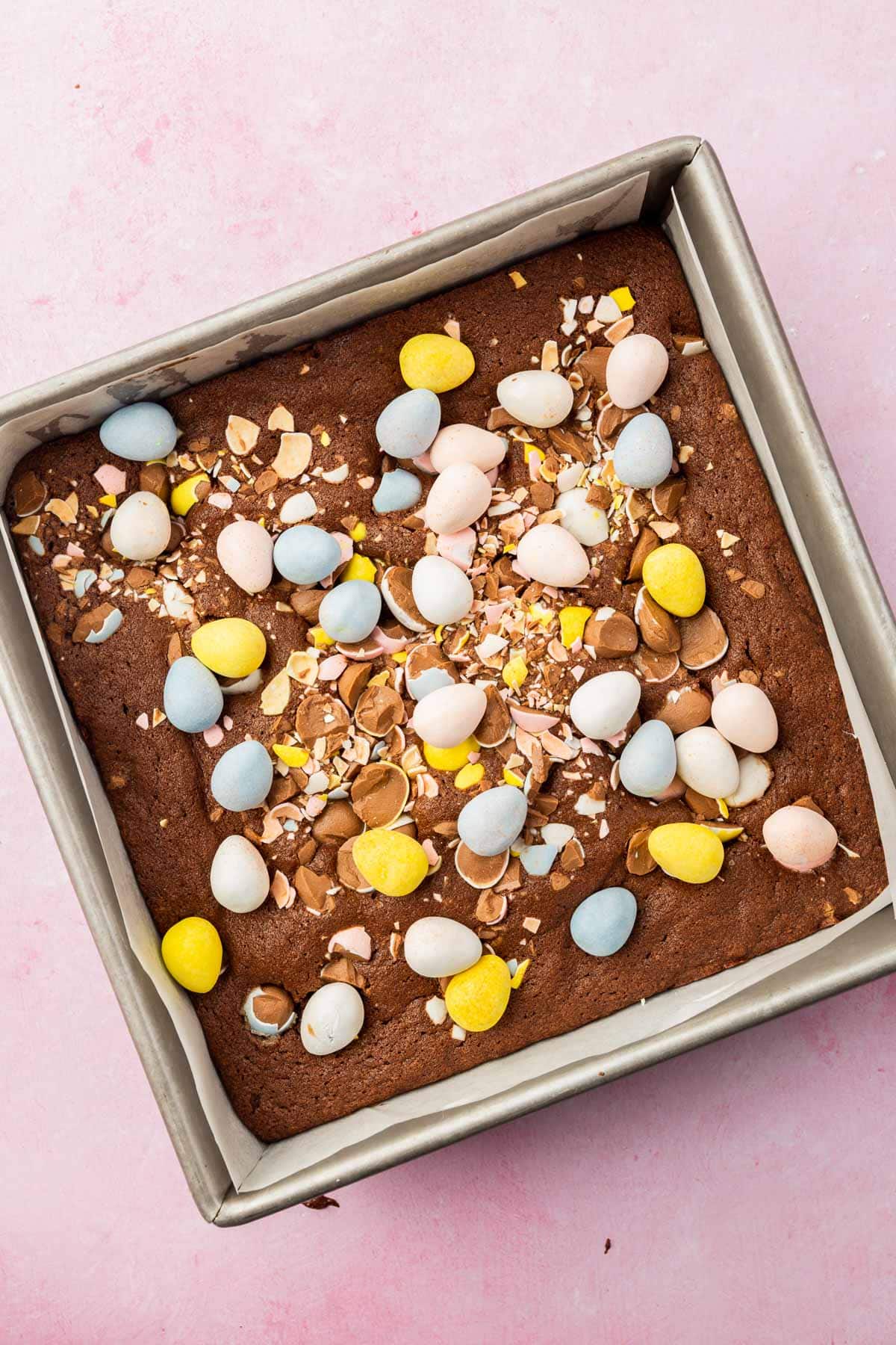 A square baking dish with brownies topped with mini chocolate eggs in it.