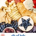 A close up of a red, white and blue charcuterie board with a brie round with a star cut out of it and filled with blueberries, meats, cheeses, crackers, and fresh strawberries.