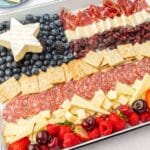 Cheese, meat, crackers and fresh berries assembled on a white baking pan to resemble an American flag.
