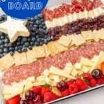 A close up of a 4th of July charcuterie board made to look like an American flag with blueberries, brie, crackers, cured meats, cheddar cheese, cherries, raspberries, strawberries and dried cranberries.