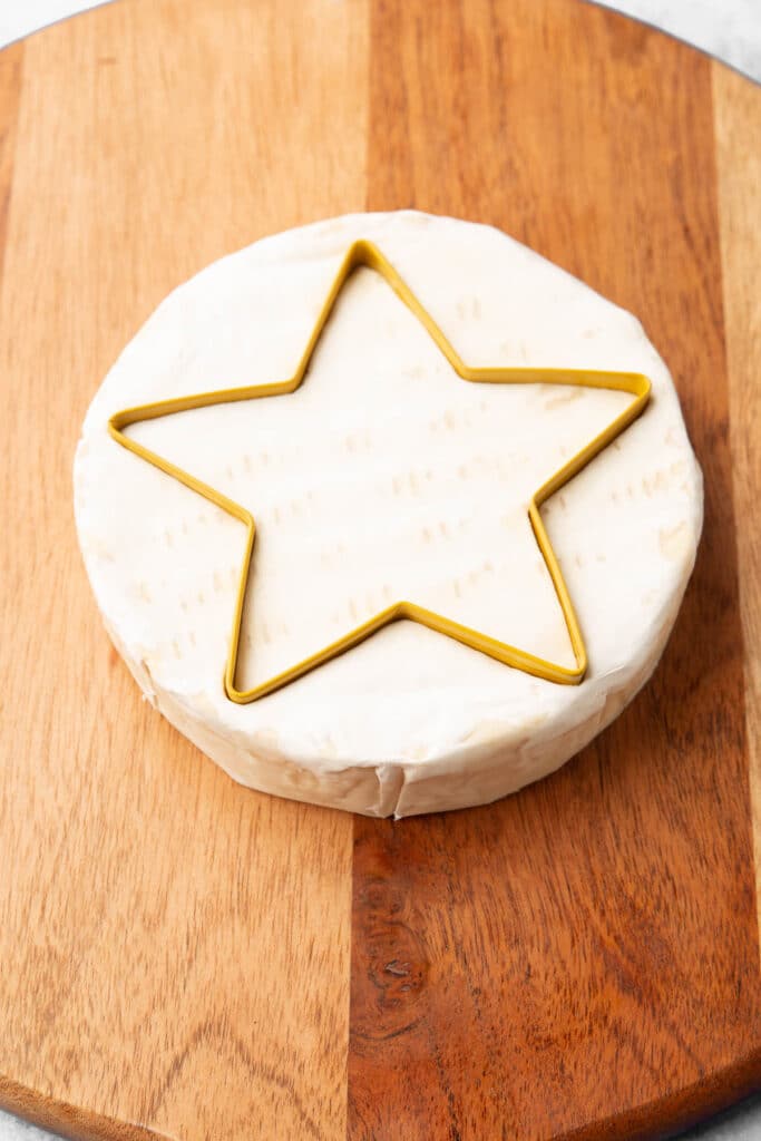 A brie round with a star shaped cookie cutter in it.