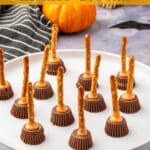 butter-pretzel-witch-brooms-pin.jpg Pinterest graphic featuring peanut butter cup pretzel witch brooms on a plate with orange text overlay reading “Halloween Chocolate Pretzel Witches’ Brooms.”