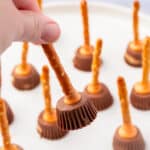 Close-up of a hand holding one peanut butter cup pretzel witch broom.