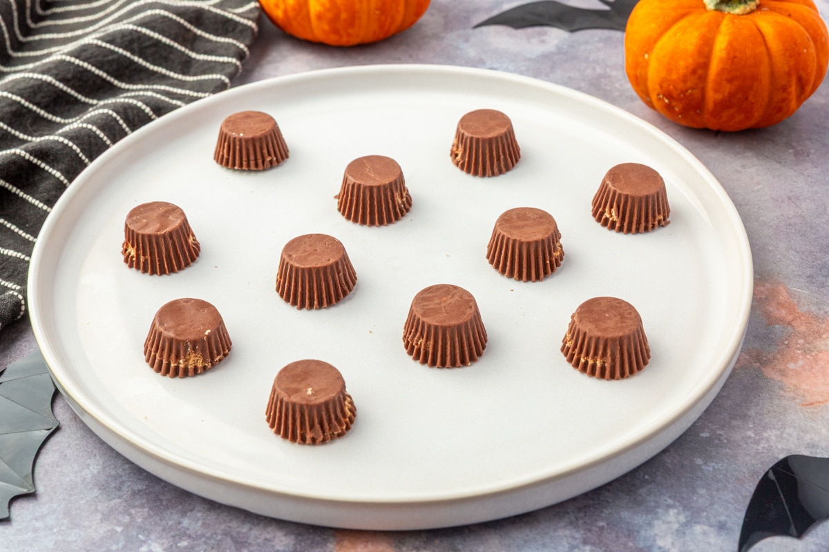 Mini peanut butter cups arranged upside down on a white plate, ready to assemble Halloween witch broom treats.