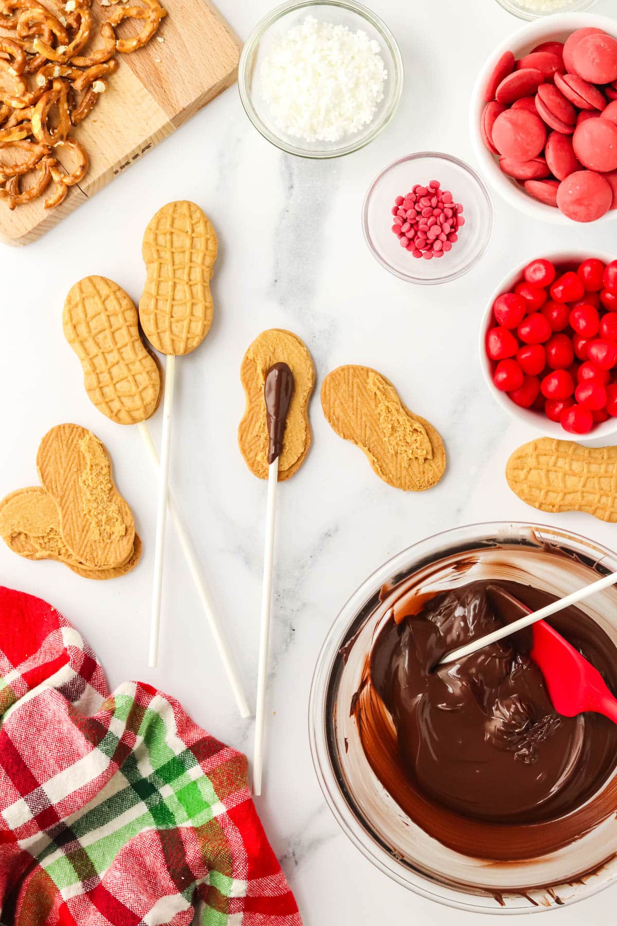 Nutter Butter cookies with candy sticks inserted next to a bowl of melted chocolate.