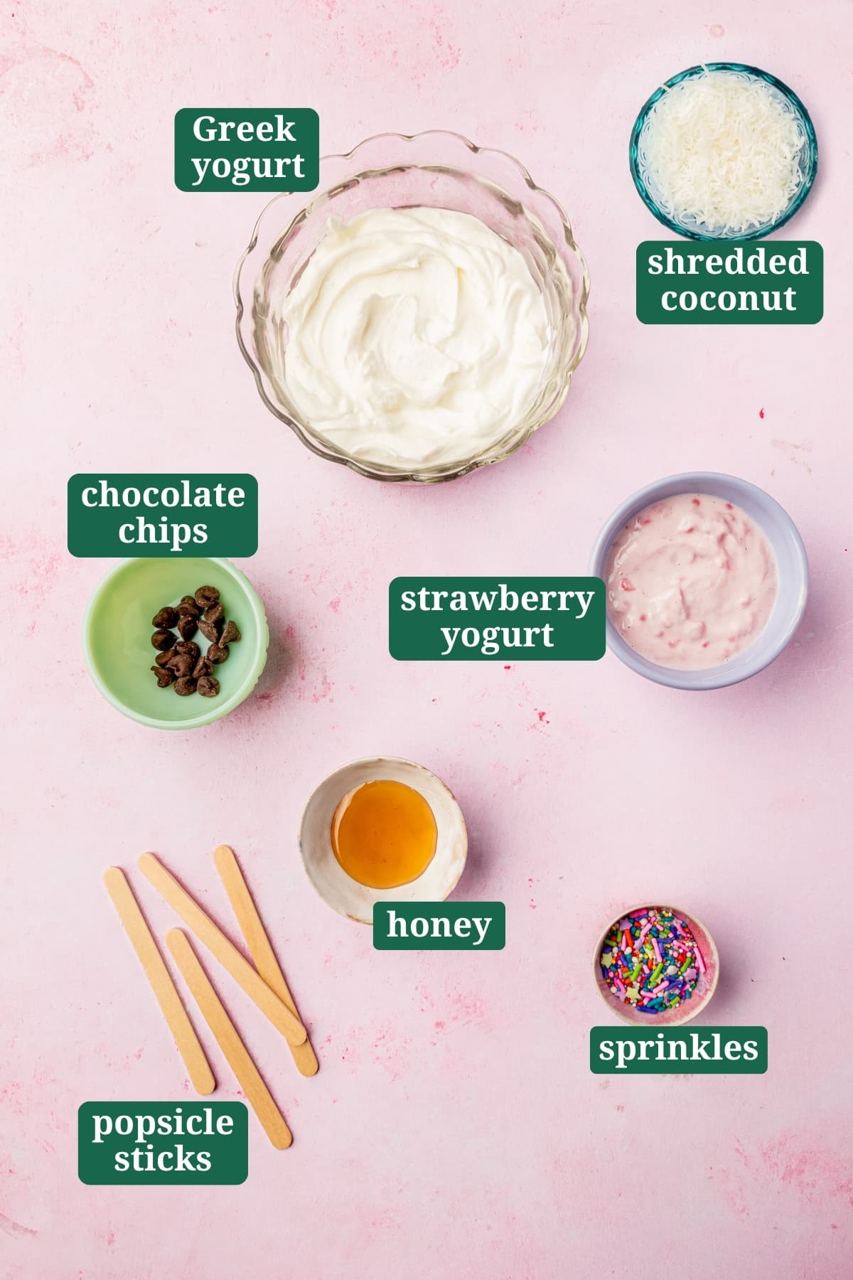 Ingredients for Easter bunny frozen yogurt pops including Greek yogurt, strawberry yogurt, honey, chocolate chips, sprinkles, and shredded coconut.