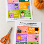 Two printed Halloween lunchbox notes sheets with colorful cards featuring jokes and fun facts, with a real pumpkin and scissors alongside.